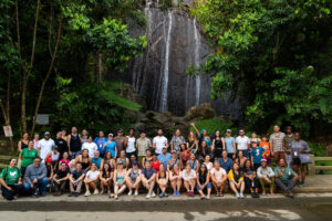 Large group gathered under a waterfall